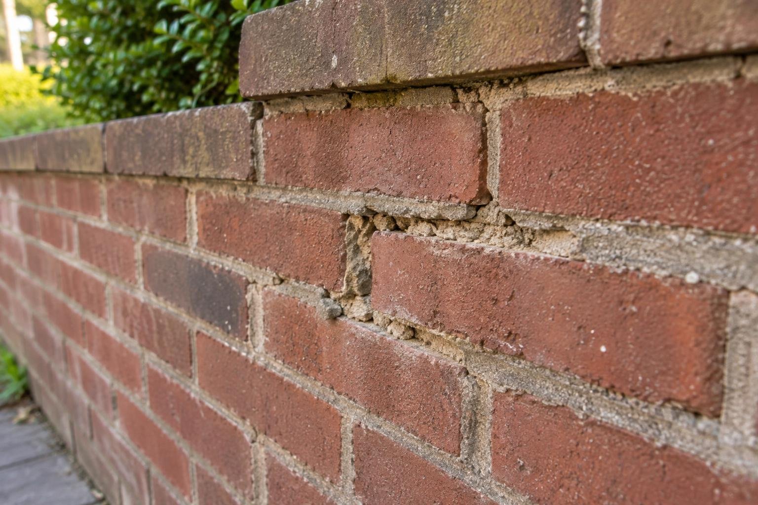 Recessed and deteriorated mortar joints between intact red bricks.
