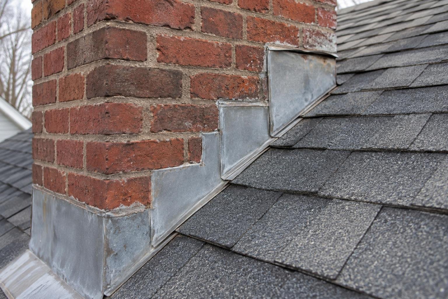 Chimney flashing at a shingle roof with a visible separation that warrants inspection.